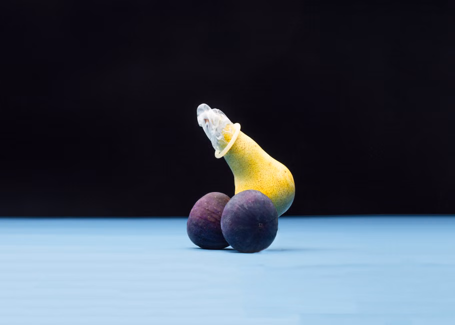 Creative representation of safe sex using a condom on a pear with figs, highlighting sexual education.